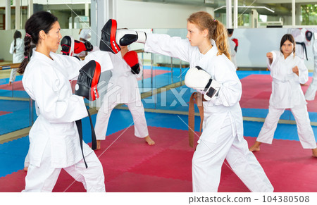 Girl launching blows on focus punch mitts 104380508