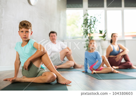 Boy performs asana lord of fish for yoga class with his family Boy performs asana lord of fish for yoga class with his family 104380603