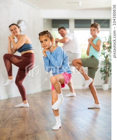 Family with two children dancing in studio 104380636