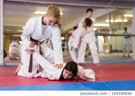 Boys performing arm lock movement during karate training 104380696
