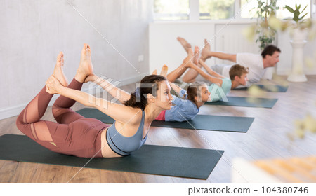 Family with two children doing yoga in studio 104380746