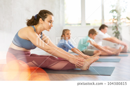 Adult woman with family practicing yoga in studio Adult woman with family practicing yoga in studio 104380815
