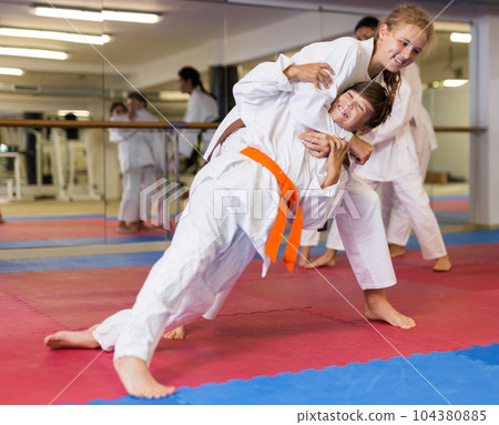 Girl doing throw over her shoulder at self-defense lesson 104380885