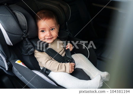 happy baby sitting in infant car seat, safety chair travelling 104381194