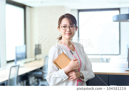 A woman holding a notebook and standing in the office 104381219