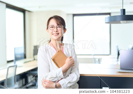 A woman holding a notebook and standing in the office 104381223