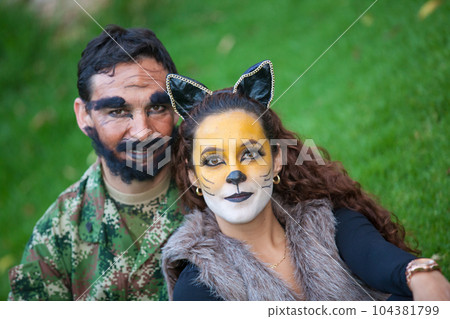 Young couple wearing wolf and woodcutter costumes. Real family having fun while using costumes of the Little red riding hood tale in Halloween. 104381799