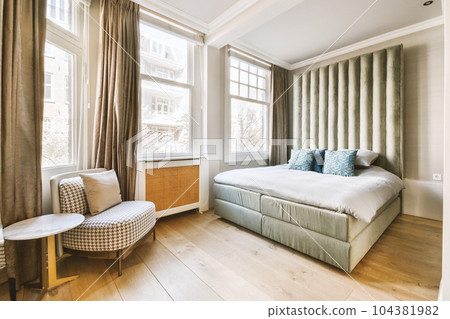 a bedroom with a bed, chair and window overlooking the cityscapearn com logo on the wall 104381982