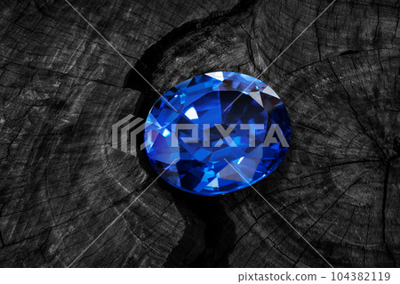 precious natural blue gemstone, blue sapphire on wooden black background 104382119