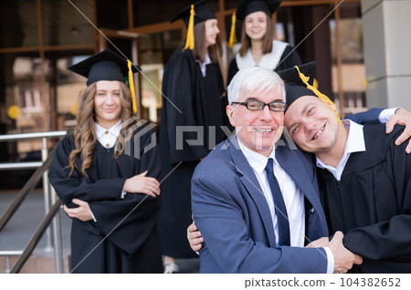 A gray-haired male teacher congratulates students on their graduation from the university. A gray-haired male teacher congratulates students on their graduation from the university. 104382652