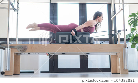 Woman doing pilates exercise on cadillac reformer machine. Woman doing pilates exercise on cadillac reformer machine. 104382881