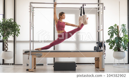 Beautiful asian woman doing splits on a reformer.  104382902