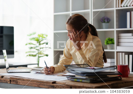 Asian business woman feel stress with works, uses a laptop, makes a report to a finance company. Accounting and financial concept Asian business woman feel stress with works, uses a laptop, makes a report to a finance company. Accounting and financial concept 104383059
