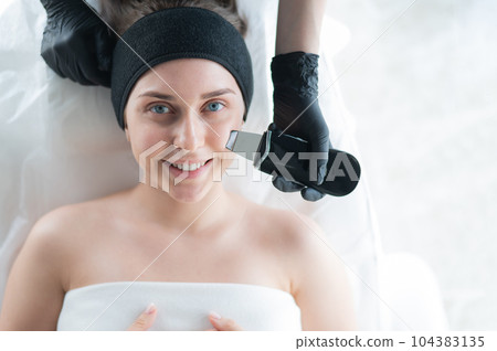 Woman on ultrasonic cleaning procedure. Hardware cosmetology. Woman on ultrasonic cleaning procedure. Hardware cosmetology. 104383135