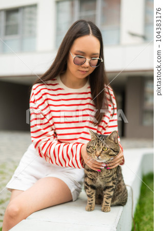 Young woman and tabby cat sitting on a bench outdoors. Young woman and tabby cat sitting on a bench outdoors. 104383176
