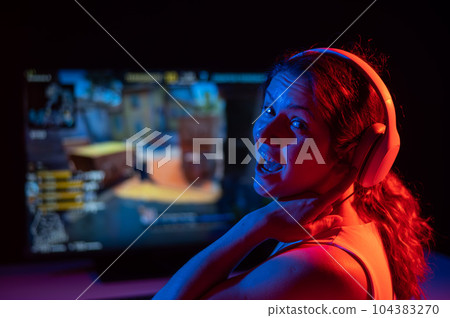 Caucasian woman asks for some more time to play computer in neon light in the dark. Caucasian woman asks for some more time to play computer in neon light in the dark. 104383270