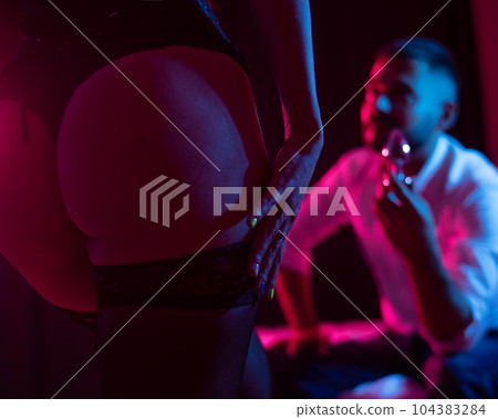 Bearded caucasian man holding an anal plug. Close-up of female buttocks in underwear. Sexual preferences of the couple. 104383284