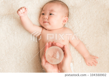 Baby's hand and mom's hand holding a glass globe 104388902