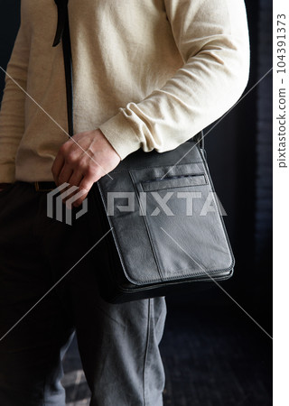 close-up photo of black messanger leather bag on mans shoulder 104391373