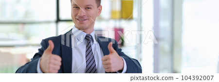 Successful businessman in suit showing thumbs up in office 104392007