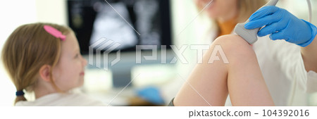 Doctor pediatrician conducting ultrasound examination of knee joint of child in clinic closeup Doctor pediatrician conducting ultrasound examination of knee joint of child in clinic closeup 104392016