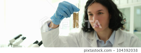 Chemist scientist holding test tubes with grains in laboratory closeup Chemist scientist holding test tubes with grains in laboratory closeup 104392038