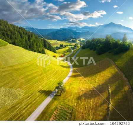 Aerial view of country road in green meadows at sunset in summer Aerial view of country road in green meadows at sunset in summer 104392723