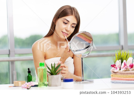 A young woman makes a beautiful makeup in the bathroom in front of the mirror A young woman makes a beautiful makeup in the bathroom in front of the mirror 104393253