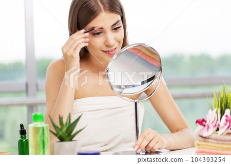 Beautiful woman using mascara on eyelash in bathroom in the morning time Beautiful woman using mascara on eyelash in bathroom in the morning time 104393254