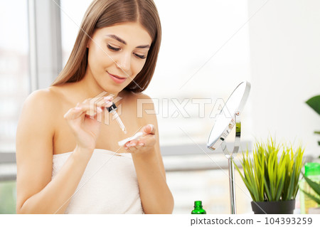 A young woman makes a beautiful makeup in the bathroom in front of the mirror A young woman makes a beautiful makeup in the bathroom in front of the mirror 104393259