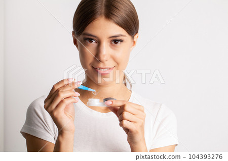 A young woman puts on contact lenses in her apartment 104393276