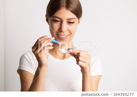 A young woman puts on contact lenses in her apartment 104393277
