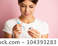 A young woman puts on contact lenses in her apartment 104393283