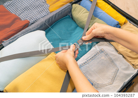View of female hands packing suitcase for summer vacation. View of female hands packing suitcase for summer vacation. 104393287