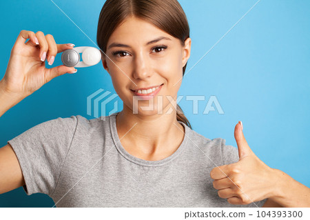 A young woman puts on contact lenses in her apartment 104393300