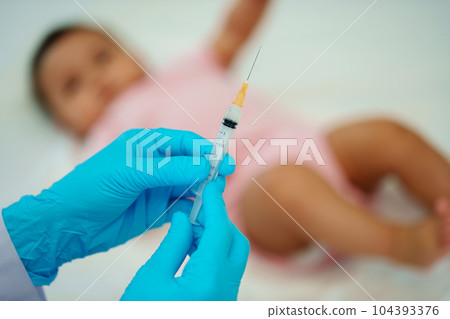 doctor holding syringe and preparing vaccine giving injection to baby 104393376