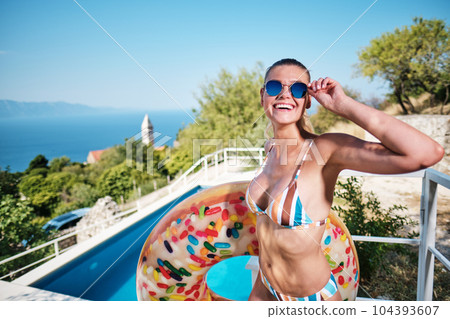 WOMAN spends time by the pool. in the background the ocean. summer holidays. 104393607