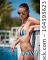 WOMAN spends time by the pool. in the background the ocean. summer holidays. 104393623