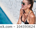 WOMAN spends time by the pool. in the background the ocean. summer holidays. 104393624