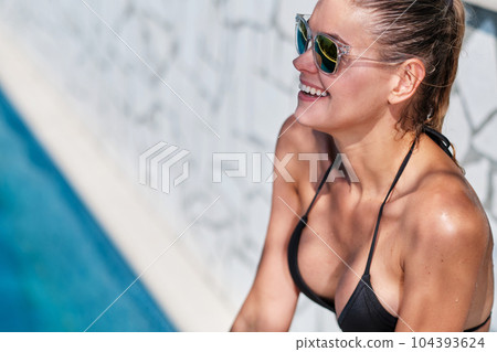 WOMAN spends time by the pool. in the background the ocean. summer holidays. WOMAN spends time by the pool. in the background the ocean. summer holidays. 104393624