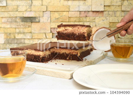 Coconut Cake on white plate with a spoon and caramel sauce 104394090