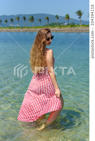 Bright blond young woman standing in sea in summer Bright blond young woman standing in sea in summer 104394118