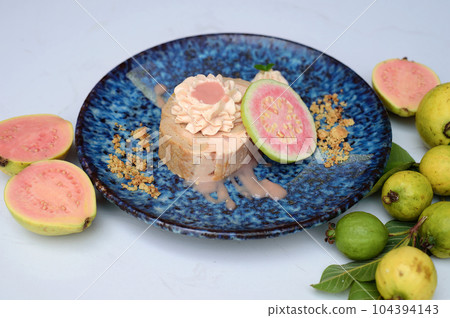 Guava Roll Cake on blue plate on light background with ripe guava fruit 104394143