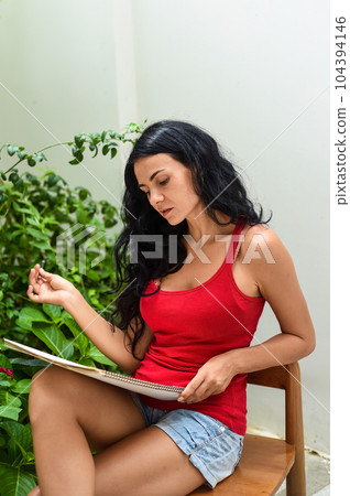 Ukrainian woman artist and illustrator thinking about idea of a drawing, sitting on a chair with a pencil 104394146