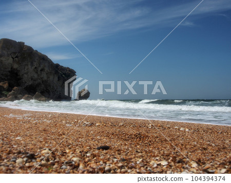 View of the rocky seashore. Fantastic view of the rocky shore on a sunny day with blue sky. A picturesque and magnificent scene. The concept of active recreation, travel. View of the rocky seashore. Fantastic view of the rocky shore on a sunny day with blue sky. A picturesque and magnificent scene. The concept of active recreation, travel. 104394374