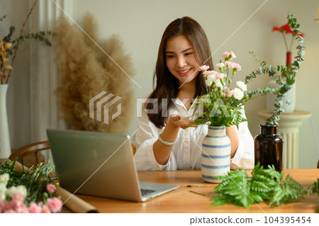 Attractive young housewife creating beautiful bouquet with different flowers in cozy home 104395454