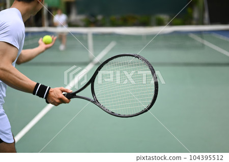 Tennis player serving tennis ball during a match on open court. Sport, fitness, training and active life concept Tennis player serving tennis ball during a match on open court. Sport, fitness, training and active life concept 104395512