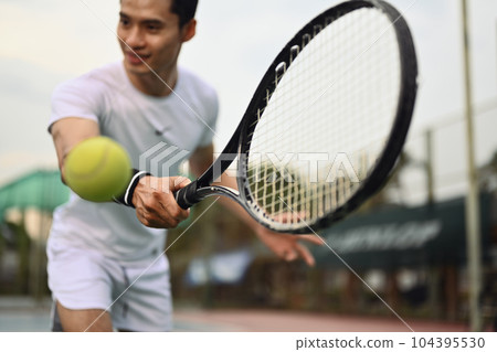 Shot of male tennis player hitting ball with racket. Sport, fitness, training and active life concept 104395530