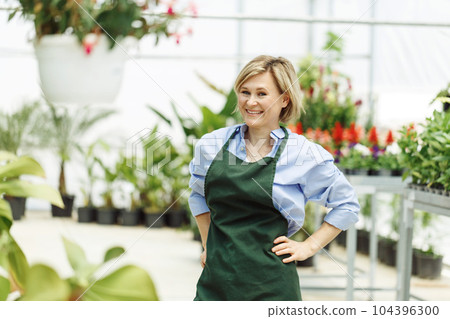 Woman is owning small business greenhouse store. Female entrepreneur. Woman is owning small business greenhouse store. Female entrepreneur. 104396300