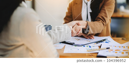 Business people shaking hands during a meeting. Two happy mature businesswomen . Business people shaking hands during a meeting. Two happy mature businesswomen . 104396952